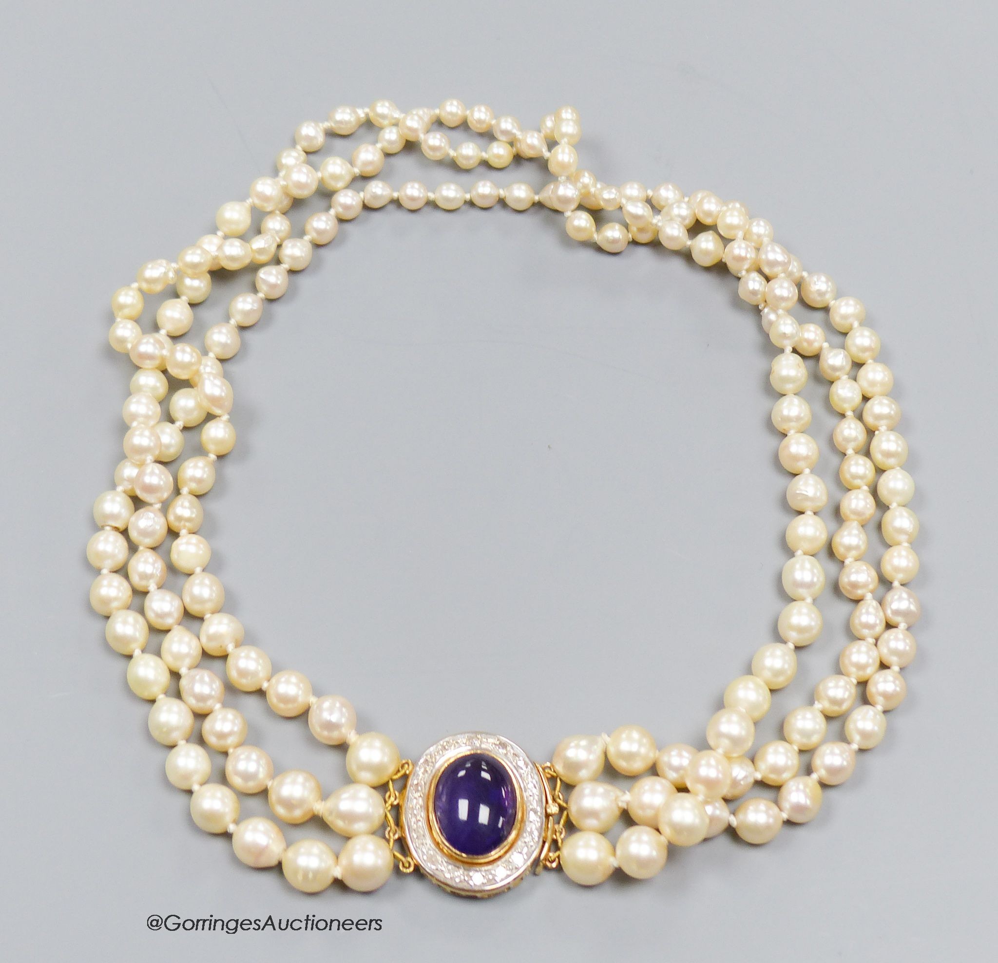 A three strand cultured pearl necklace with cabochon amethyst and diamond set 18ct gold clasp, 40cm.